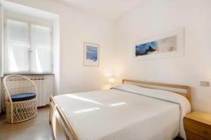 a white bedroom with a bed and a chair at Nonna Adele in Sestri Levante