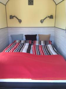 a bed with a red blanket and two lights on the wall at Traumwagen an der Mühle in Thalingburen