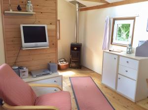 a living room with a tv and a chair at Traumwagen an der Mühle in Thalingburen
