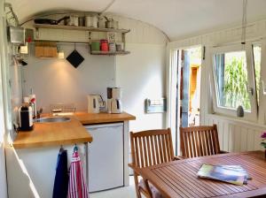 a kitchen with a sink and a table with chairs at Traumwagen an der Mühle in Thalingburen