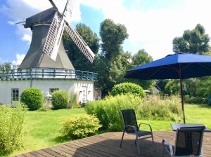 a table and chairs with an umbrella and a windmill at Traumwagen an der Mühle in Thalingburen
