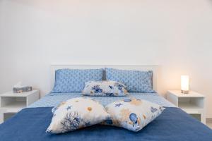 a blue bed with four pillows on it at Appartamento Le Primule in Agrigento