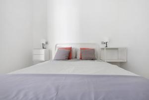 a white bedroom with a large white bed with red pillows at La Corte A1 in Antigua