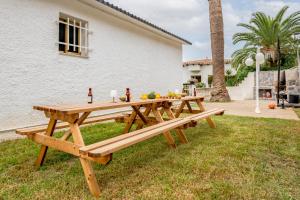 a wooden picnic table in the grass in front of a house at Oasis Salou Pool Beach and Bbq in Salou