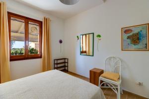 a bedroom with a bed and a chair and a window at Casa Donatella Torre dei Corsari in Torre Dei Corsari