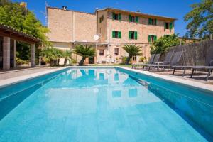 a swimming pool with chairs and a building in the background at Villa Rae in Sóller