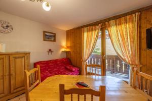 a living room with a table and a red couch at Le jardin des neiges in Praz-sur-Arly