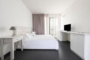 a white bedroom with a bed and a desk and a television at Case Vacanze Otranto in Otranto +112 photos