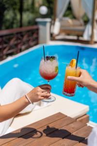 two people holding cocktails on a table near a pool at Doliva Studio with private pool in Agios Gordios