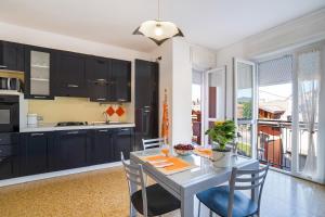 a kitchen with black cabinets and a table with chairs at Iris Apartment Lago Maggiore in Angera