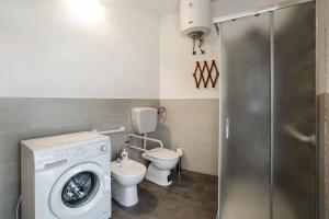 a bathroom with a washing machine and a toilet at Iris Apartment Lago Maggiore in Angera +15 photos
