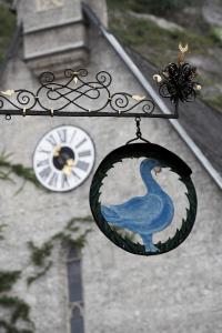a clock tower with a blue peacock ornament and a clock at artHotel Blaue Gans in Salzburg
