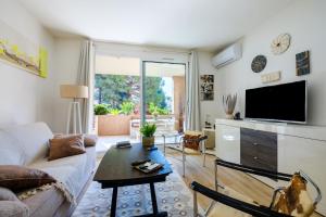 a living room with a couch and a tv at Appartement Vaugrenier Presidences in Villeneuve-Loubet