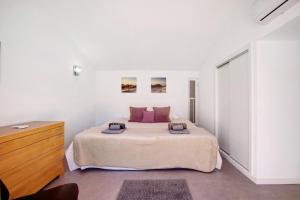 a white bedroom with a large bed and a dresser at Villa Lynn - Quadradinhos in Almancil
