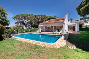 a swimming pool in front of a house at Villa Lynn - Quadradinhos in Almancil