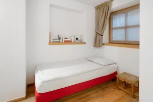 a red and white bed in a room with a window at Chalet Pieri - Appartamento Bedogn in Bormio +5 photos