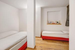 two beds in a room with white walls and a mirror at Chalet Pieri - Appartamento Bedogn in Bormio