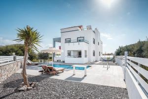 a white house with a pool and a palm tree at White Pearl in Lachania