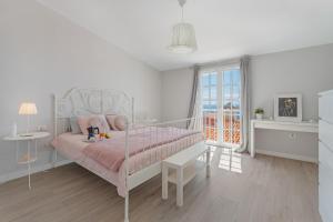 a white bedroom with a pink bed and a window at Casa el Jable in Guía de Isora