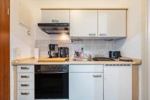 a kitchen with white cabinets and a stove top oven at Backbordkajüte am Steinhuder Meer in Wunstorf