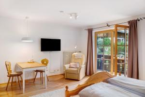 a bedroom with a bed and a table and a chair at Ferienwohnung Zugspitznest in Grainau