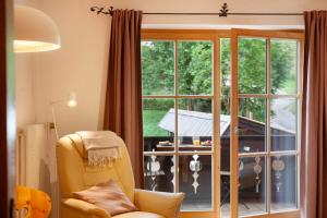 a living room with a yellow chair and a large window at Ferienwohnung Zugspitznest in Grainau