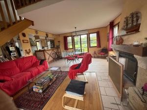 a living room with a red couch and a fireplace at Les Buissons in Saint-Pierre-le-Vieux