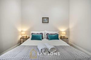 a bedroom with a white bed with blue pillows at Sea You Soon I Seafront Stay in Portsmouth