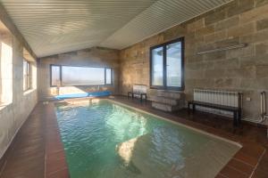 a swimming pool in a room with a stone wall at El Arrebol Rural in El Espinar