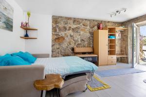 a bedroom with a bed and a stone wall at Estúdio Azul in Moledo +18 photos