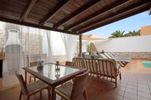 a dining room with a glass table and chairs on a patio at El Cortijo in La Oliva