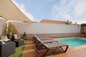 a patio with a pool and lounge chairs next to a building at El Cortijo in La Oliva