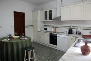 a kitchen with white cabinets and a green table in it at Casa do Sossego in Safara