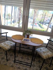 a table and two chairs in a room with two windows at Vista al Mar in Denia +10 photos