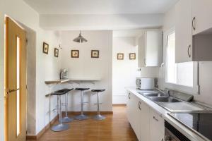 a kitchen with white cabinets and bar stools at Oleanda in Alcudia