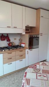 a kitchen with white cabinets and a stove top oven at Mansarda le Chateau in Aymavilles