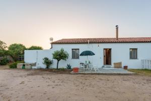 a white house with a table and an umbrella at Casa vacanza Macciunitta in Arzachena
