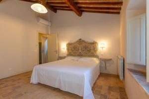 a bedroom with a white bed and a wooden floor at Borgo Ariano near Volterra by PosarelliVillas in Volterra +198 photos