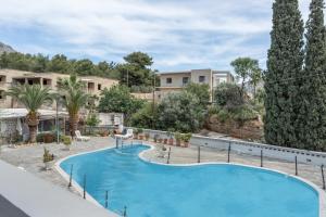 a swimming pool in a resort with trees and buildings at Ilias Voula Studios in Kalymnos