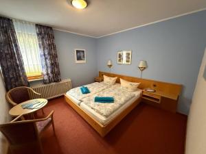 a bedroom with a bed and a table and a chair at Waldhotel Einstein in Kirchhundem