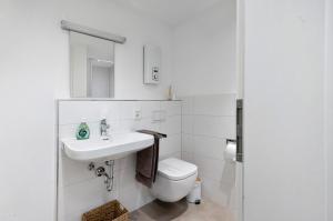 a white bathroom with a sink and a toilet at Adlernest mit Weinbergblick in Trittenheim +7 photos