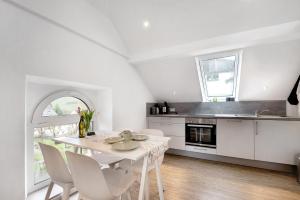 a white kitchen with a white table and chairs at Adlernest mit Weinbergblick in Trittenheim