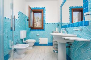a blue tiled bathroom with a toilet and a sink at Villetta Confortevole in San Teodoro +16 photos