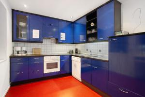 a kitchen with blue cabinets and a red floor at Gästehaus Roth in Willingen