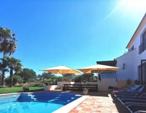 a swimming pool with umbrellas and a house at Villa Laguna - Charmy Villa in Moncarapacho
