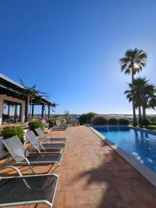 a row of lounge chairs next to a swimming pool at Villa Laguna - Charmy Villa in Moncarapacho