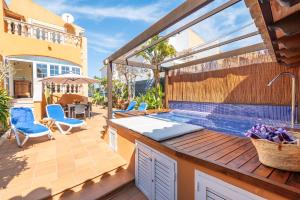a patio with a hot tub on a deck with a swimming pool at Mimosa in Alcudia
