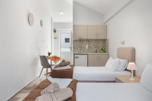 a white room with a bed and a kitchen at Ilias Voula Studios in Kalymnos