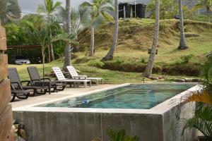 a swimming pool with chairs and a hill with palm trees at Casa AltoMar in Palomino