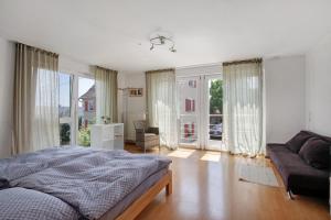 a bedroom with a bed and a couch and windows at Ferienwohnung am Hof in Zwiefalten